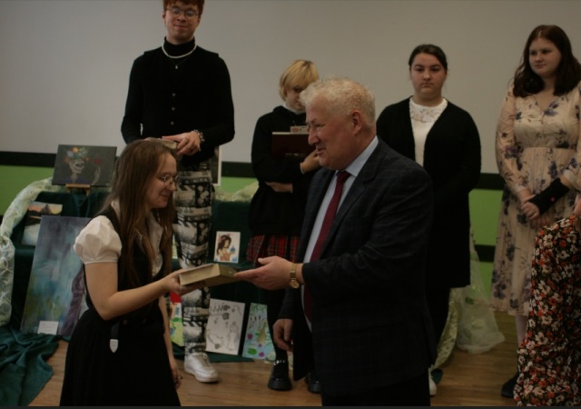 Dyrektor szkoły wręcza nagrodę zwyciężczyni konkursu recytatorskiego